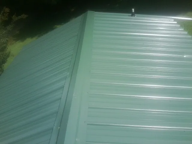 New green metal panels meeting at the ridge of a roof — Flat Roof Repair work by our crew in Bunkerville